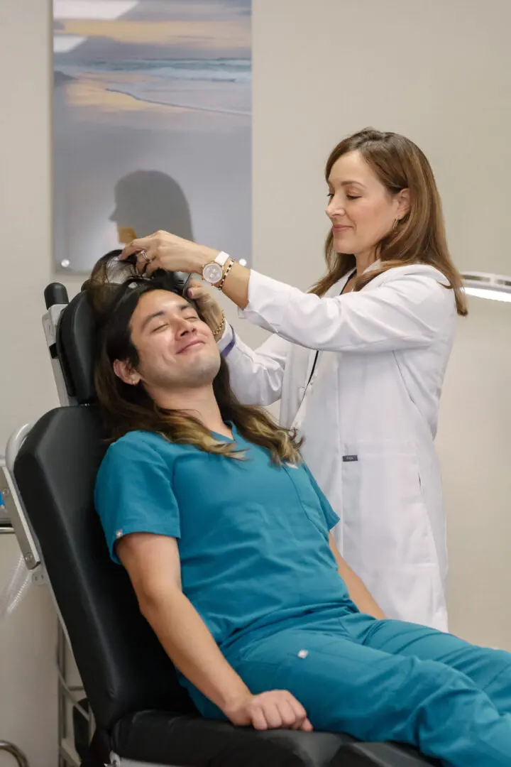 A woman is cutting the hair of a man.